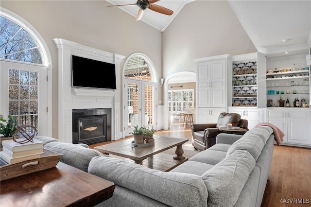 living room with crown molding, plenty of natural light, hardwood / wood-style floors, and high vaulted ceiling