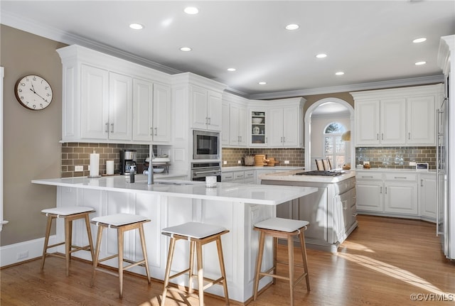 kitchen featuring built in microwave, a breakfast bar area, light hardwood / wood-style floors, and white cabinets