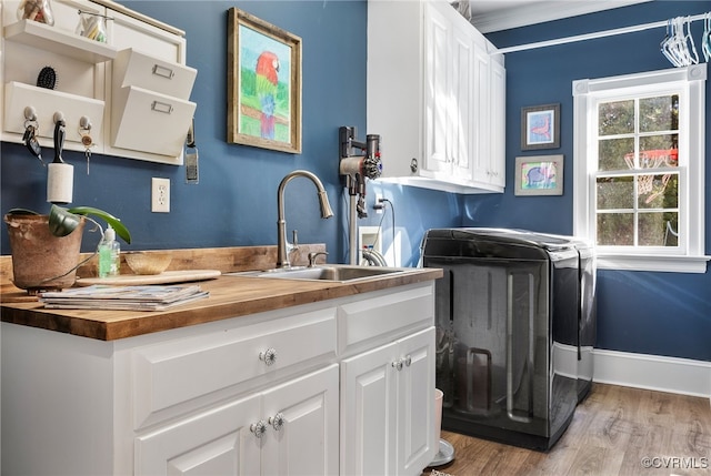 laundry room featuring sink, light hardwood / wood-style floors, cabinets, and washing machine and clothes dryer