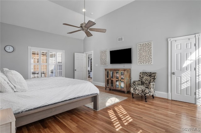 bedroom with hardwood / wood-style floors, high vaulted ceiling, and ceiling fan