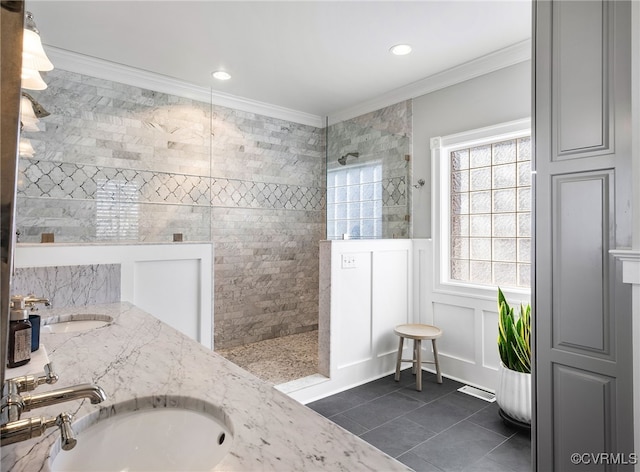 bathroom with tile patterned flooring, ornamental molding, tiled shower, and vanity