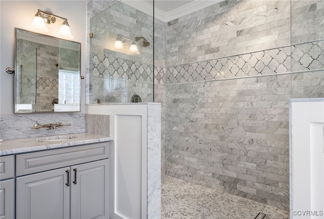 bathroom featuring a tile shower, vanity, and crown molding