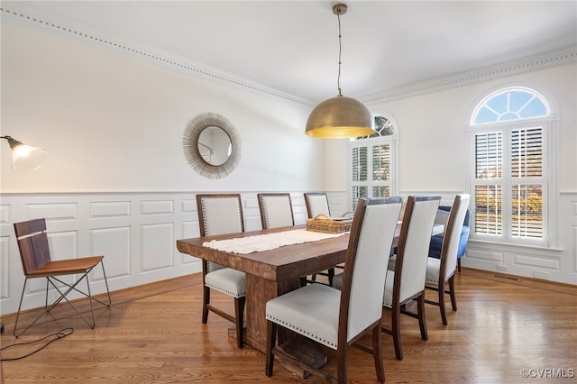 dining space with hardwood / wood-style flooring, ornamental molding, and a wealth of natural light