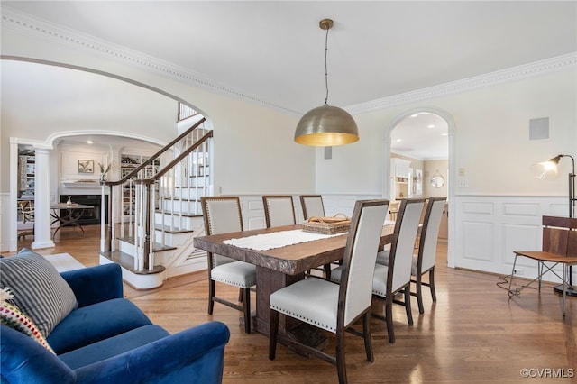 dining room featuring hardwood / wood-style flooring, ornamental molding, and ornate columns