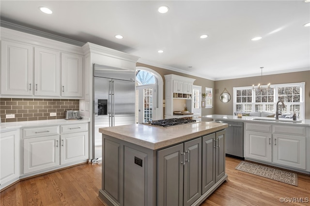 kitchen with stainless steel appliances, white cabinetry, a kitchen island, and decorative light fixtures