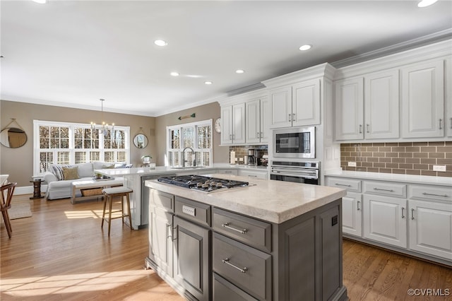 kitchen with white cabinetry, crown molding, tasteful backsplash, and stainless steel appliances