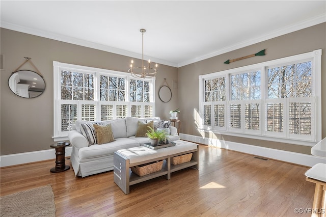 living room featuring ornamental molding, a notable chandelier, and light hardwood / wood-style floors