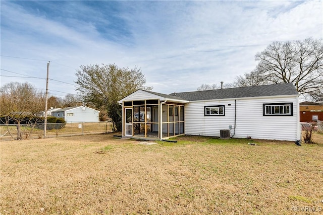 rear view of house with central AC unit, a sunroom, and a lawn