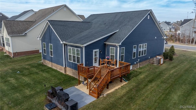 back of property featuring a shingled roof, a yard, and a deck