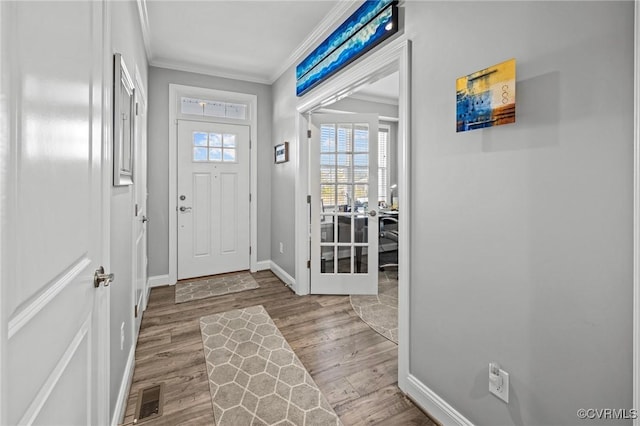 foyer entrance with ornamental molding, wood finished floors, visible vents, and baseboards