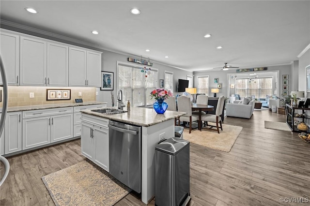 kitchen with a sink, light wood-type flooring, ornamental molding, and dishwasher