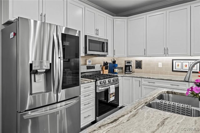 kitchen featuring appliances with stainless steel finishes, a sink, white cabinetry, and decorative backsplash