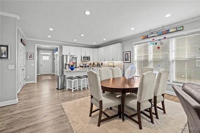 dining area with ornamental molding, recessed lighting, baseboards, and light wood finished floors