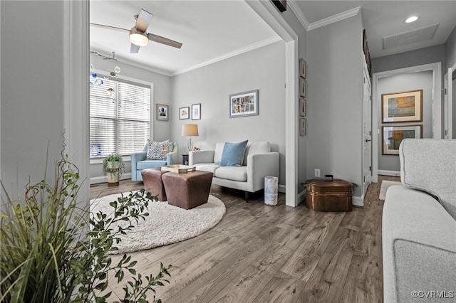 living area featuring visible vents, ornamental molding, ceiling fan, wood finished floors, and baseboards