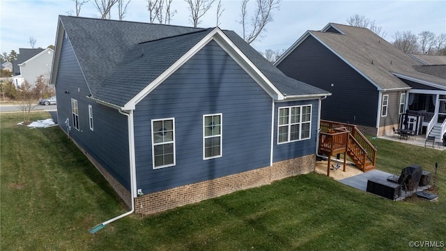 rear view of house featuring a patio area, a yard, a deck, and roof with shingles