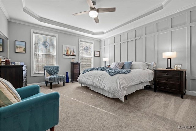 bedroom featuring carpet floors, a tray ceiling, and a decorative wall