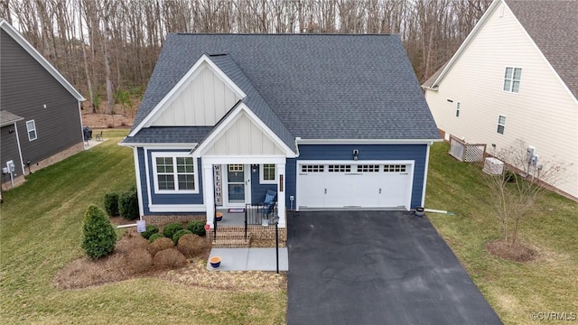 view of front of home with a shingled roof, board and batten siding, a front yard, a garage, and driveway