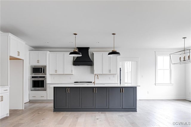 kitchen featuring premium range hood, white cabinetry, stainless steel appliances, and decorative light fixtures