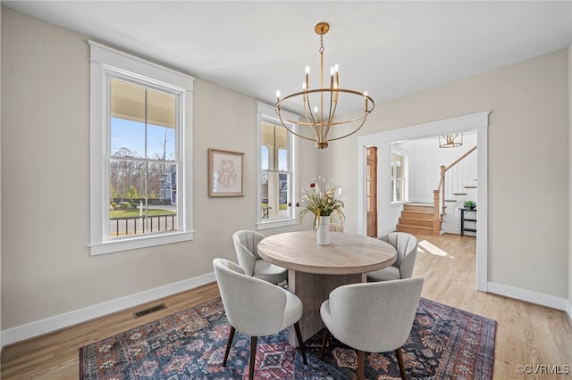 dining space with light wood-type flooring and a notable chandelier