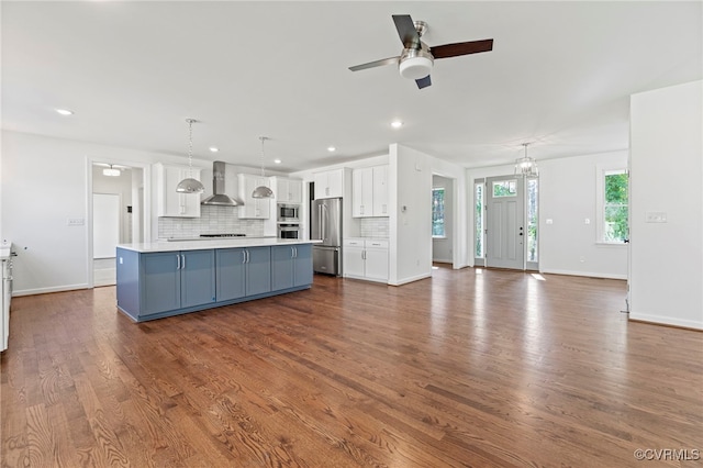 kitchen with white cabinetry, decorative light fixtures, a kitchen island, stainless steel appliances, and ceiling fan with notable chandelier