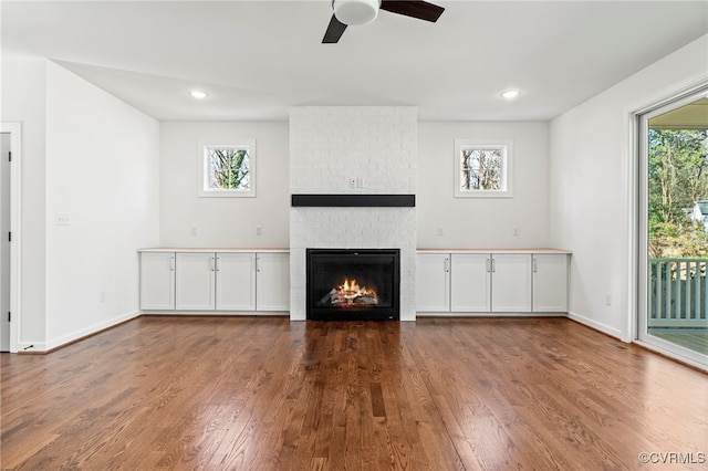 unfurnished living room with dark hardwood / wood-style floors, ceiling fan, and a fireplace