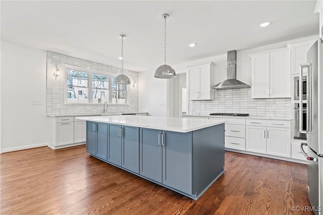 kitchen with a kitchen island, wall chimney range hood, and white cabinets