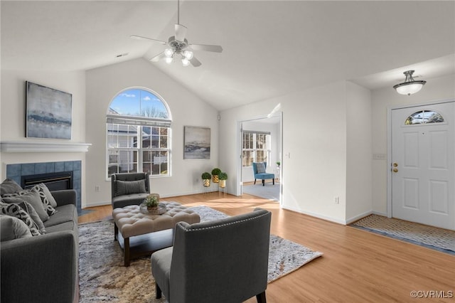 living room featuring vaulted ceiling, hardwood / wood-style floors, ceiling fan, and a fireplace