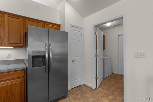 kitchen featuring lofted ceiling, separate washer and dryer, and stainless steel fridge with ice dispenser