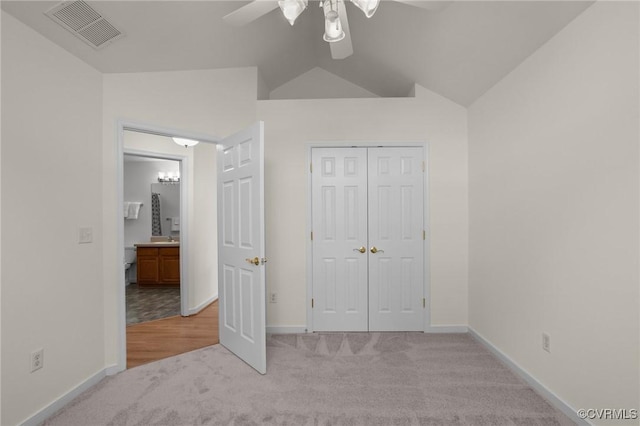 unfurnished bedroom featuring lofted ceiling, light colored carpet, a closet, and ceiling fan