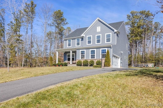 traditional home featuring a garage, aphalt driveway, and a front yard