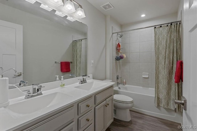 bathroom with wood finished floors, shower / bath combo with shower curtain, a sink, and visible vents