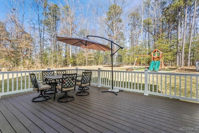 wooden terrace with outdoor dining space and a playground