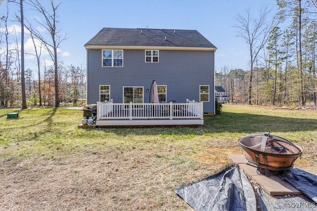 rear view of property with a yard, an outdoor fire pit, a shingled roof, and a wooden deck