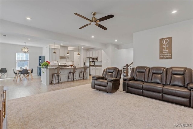 living room featuring baseboards, light wood-type flooring, a ceiling fan, and recessed lighting