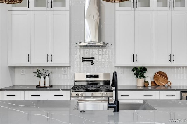 511 N 33rd St, Richmond, VA 23223 - kitchen featuring wall chimney exhaust hood, stainless steel range with gas stovetop, white cabinets, glass insert cabinets, and backsplash