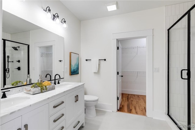 511 N 33rd St, Richmond, VA 23223 - full bathroom featuring double vanity, a stall shower, toilet, a walk in closet, and baseboards