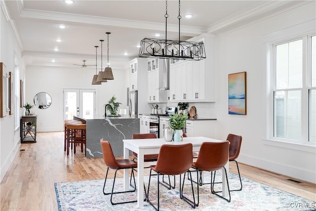 dining area featuring french doors, crown molding, and light hardwood / wood-style flooring