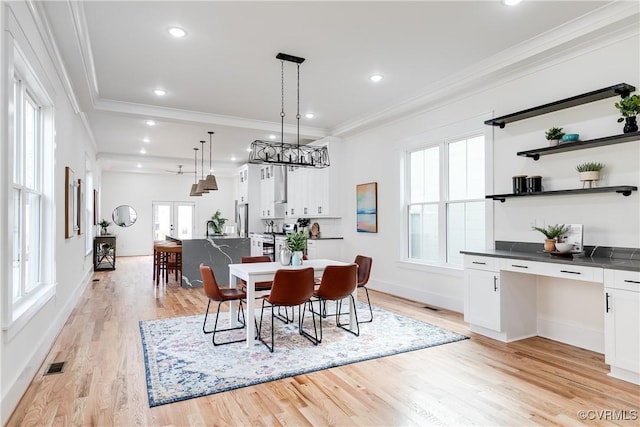 dining space with ornamental molding, built in desk, and light wood-type flooring