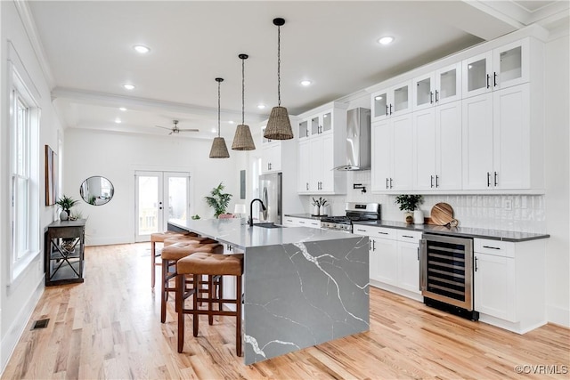 kitchen featuring beverage cooler, hanging light fixtures, a large island, stainless steel appliances, and wall chimney range hood