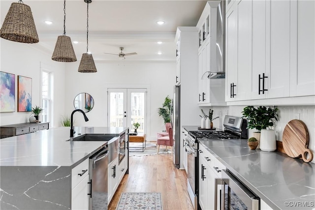 kitchen with stainless steel appliances, stainless steel counters, white cabinets, and decorative light fixtures