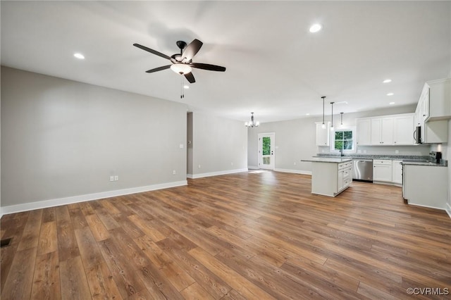 kitchen featuring pendant lighting, appliances with stainless steel finishes, a center island, white cabinets, and ceiling fan with notable chandelier