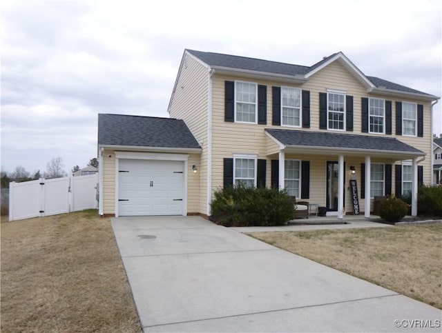 colonial-style house featuring a garage, covered porch, and a front lawn