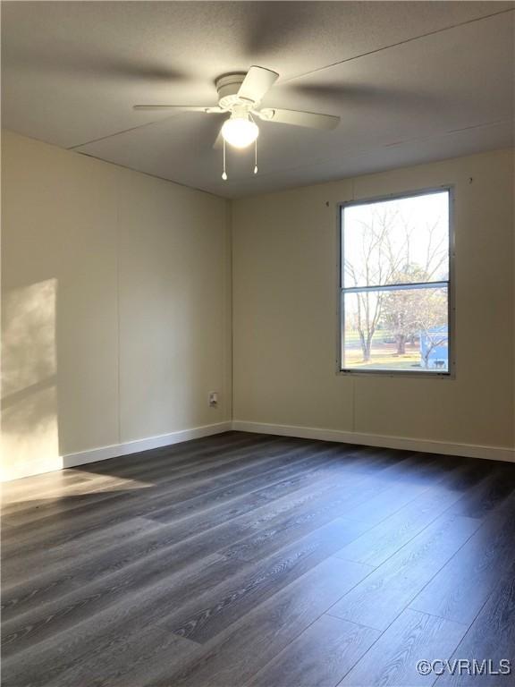 empty room with dark wood-type flooring and ceiling fan