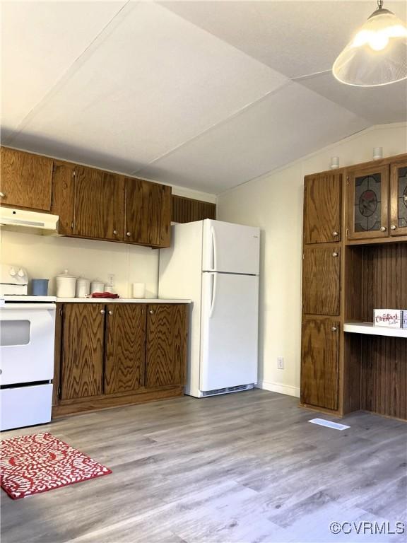 kitchen featuring lofted ceiling, decorative light fixtures, white appliances, and light hardwood / wood-style floors