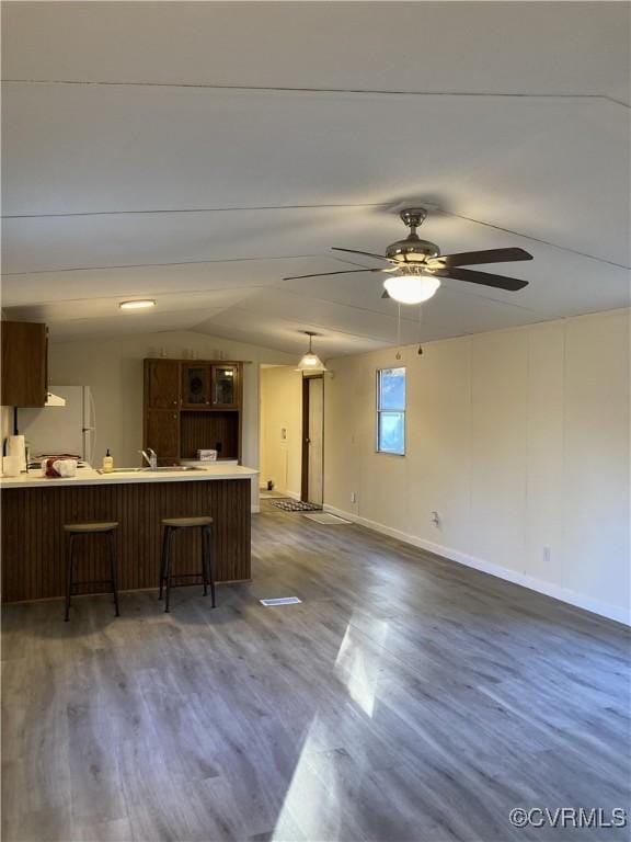 kitchen featuring lofted ceiling, dark hardwood / wood-style floors, kitchen peninsula, and a breakfast bar area