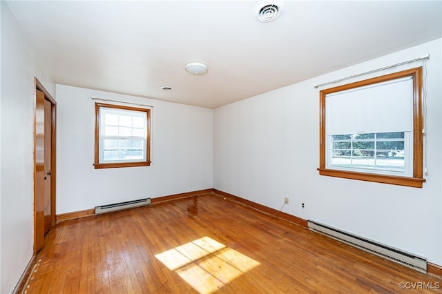 unfurnished room featuring hardwood / wood-style flooring and baseboard heating