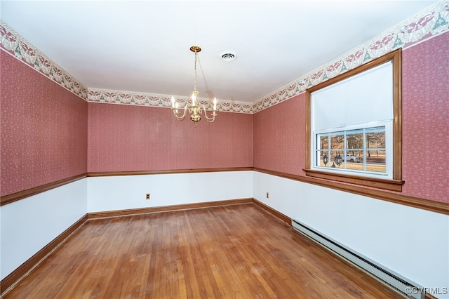 spare room featuring hardwood / wood-style flooring, a chandelier, and baseboard heating