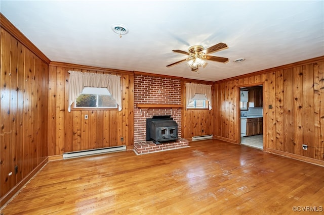 unfurnished living room featuring baseboard heating, a healthy amount of sunlight, and hardwood / wood-style flooring