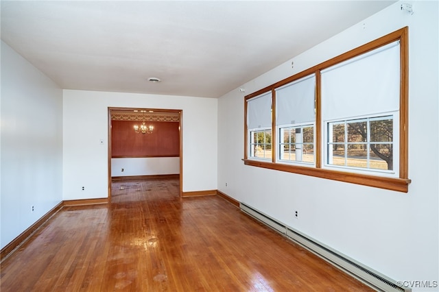 unfurnished room featuring hardwood / wood-style floors, a baseboard radiator, and a chandelier