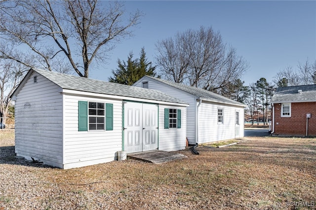 back of property with an outbuilding and a yard